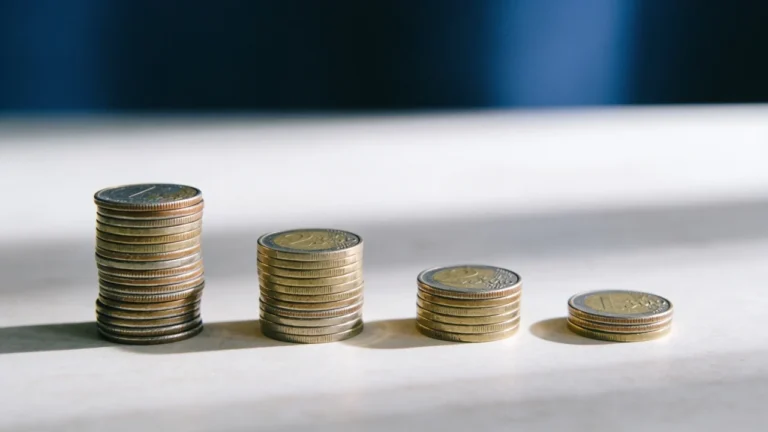 Four stacks of coins descending in height from tall to short on a neutral surface, illustrating a debt balance being paid down
